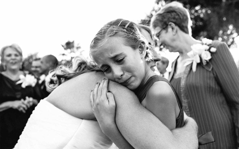 Tears flow as flower girl hugs bride at a wedding reception in Corpus Christi, Texas. Leica wedding photographer