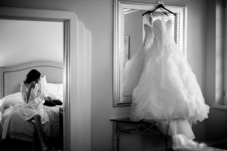 Bride on wedding day adds earrings at Hotel Galvez in Galveston Texas framed in a doorway