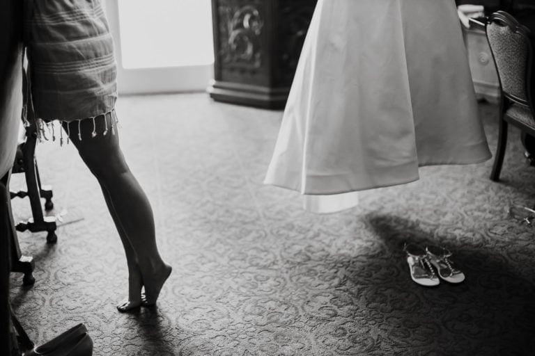 Bride arches up on her tippy toes to reach as her wedding dress hangs at Westin Riverwalk, Travis Park United Methodist wedding ceremony + Southwest School of Art Reception Spring Wedding-04