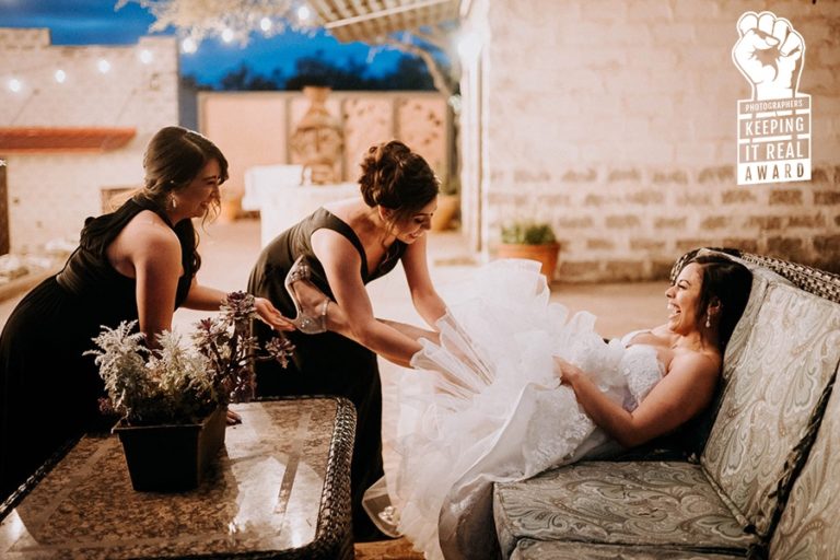 Photographers Keeping It Real - Award winning iage by Philip Thomas shows the mother and sister of bride adjusting her garter