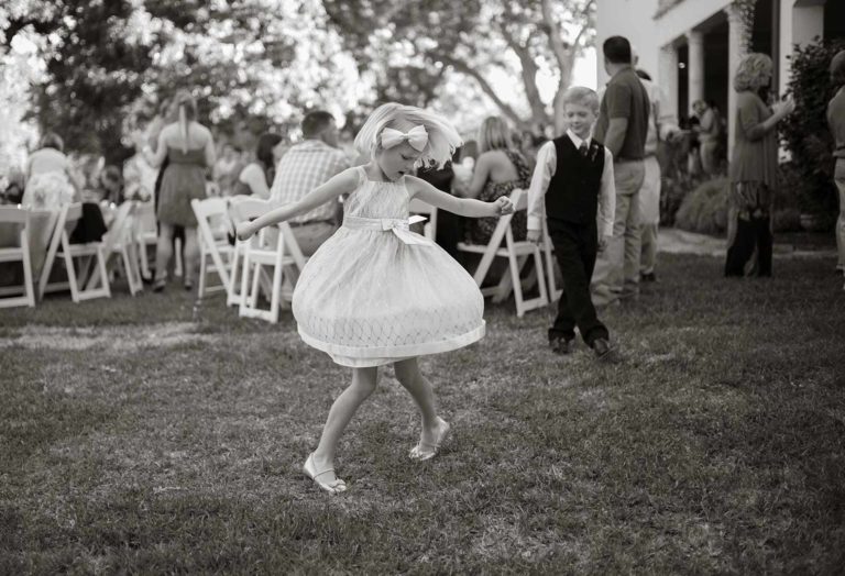 Flower girl twirls as boy looks on in an outdoor wedding reception hill country texas