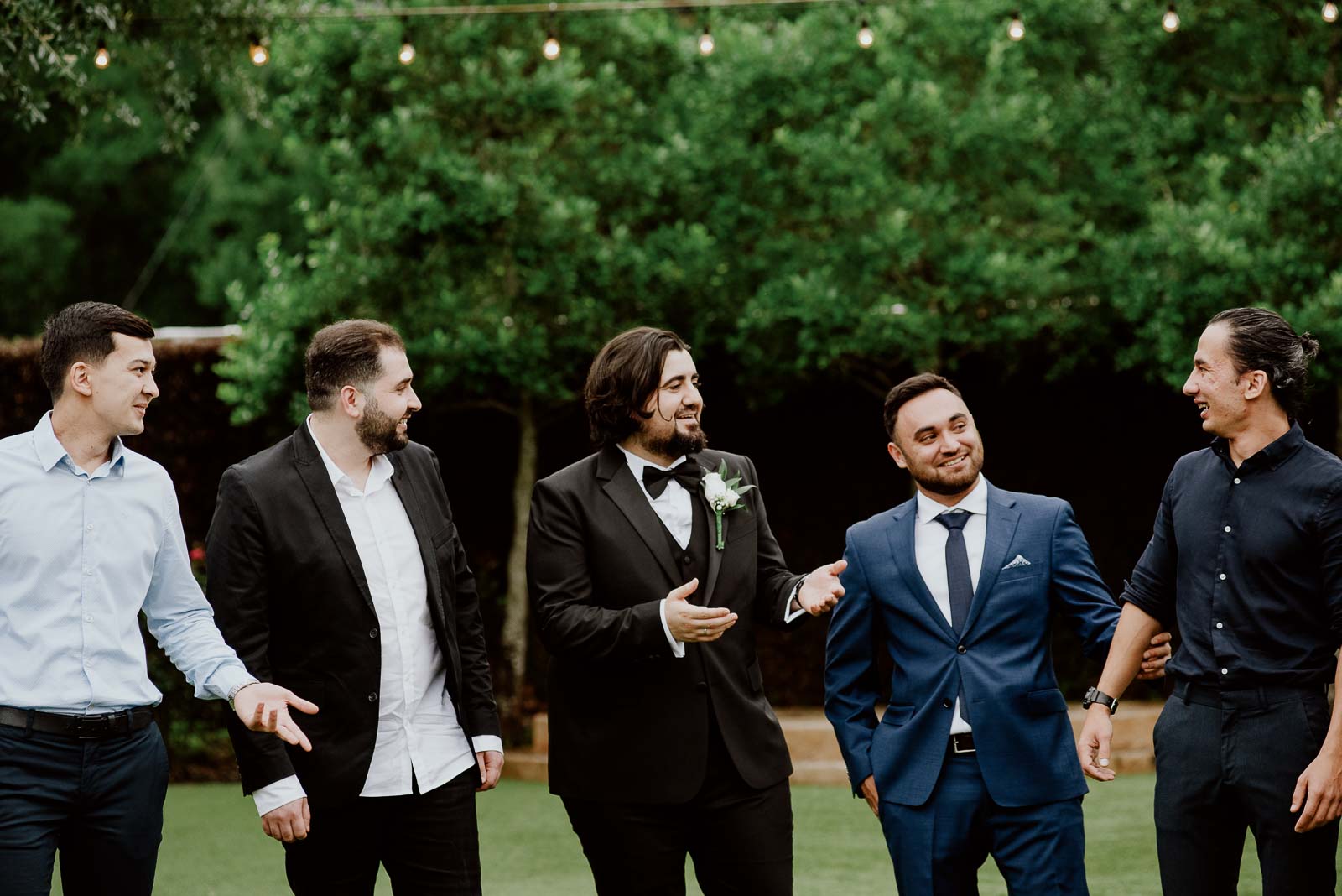 Groomsmen nd the groom joke around during formal pictures