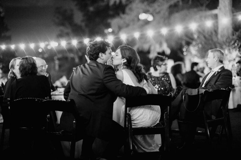 San Antonio wedding photographers Philip Thomas captures a couple steal a kiss during wedding reception under string lights at The Witte Museum Wedding photographer San Antonio Wedding Documentary Photojournalist Leica Wedding Photographer Philip Thomas