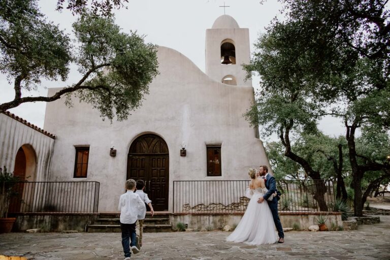 042 Two boys run toward the church oblivious to a couple photo at Lost Mission Spring Branch Texas Wedding Ceremony Reception Philip Thomas Photography L1002153