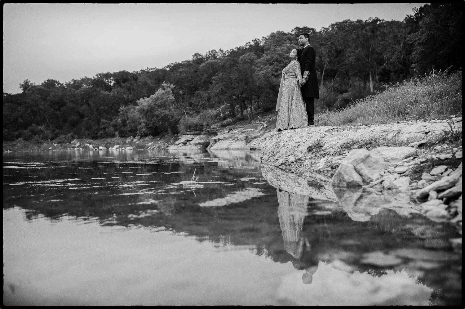 a man and woman standing on a rock near water at The Videre Estate