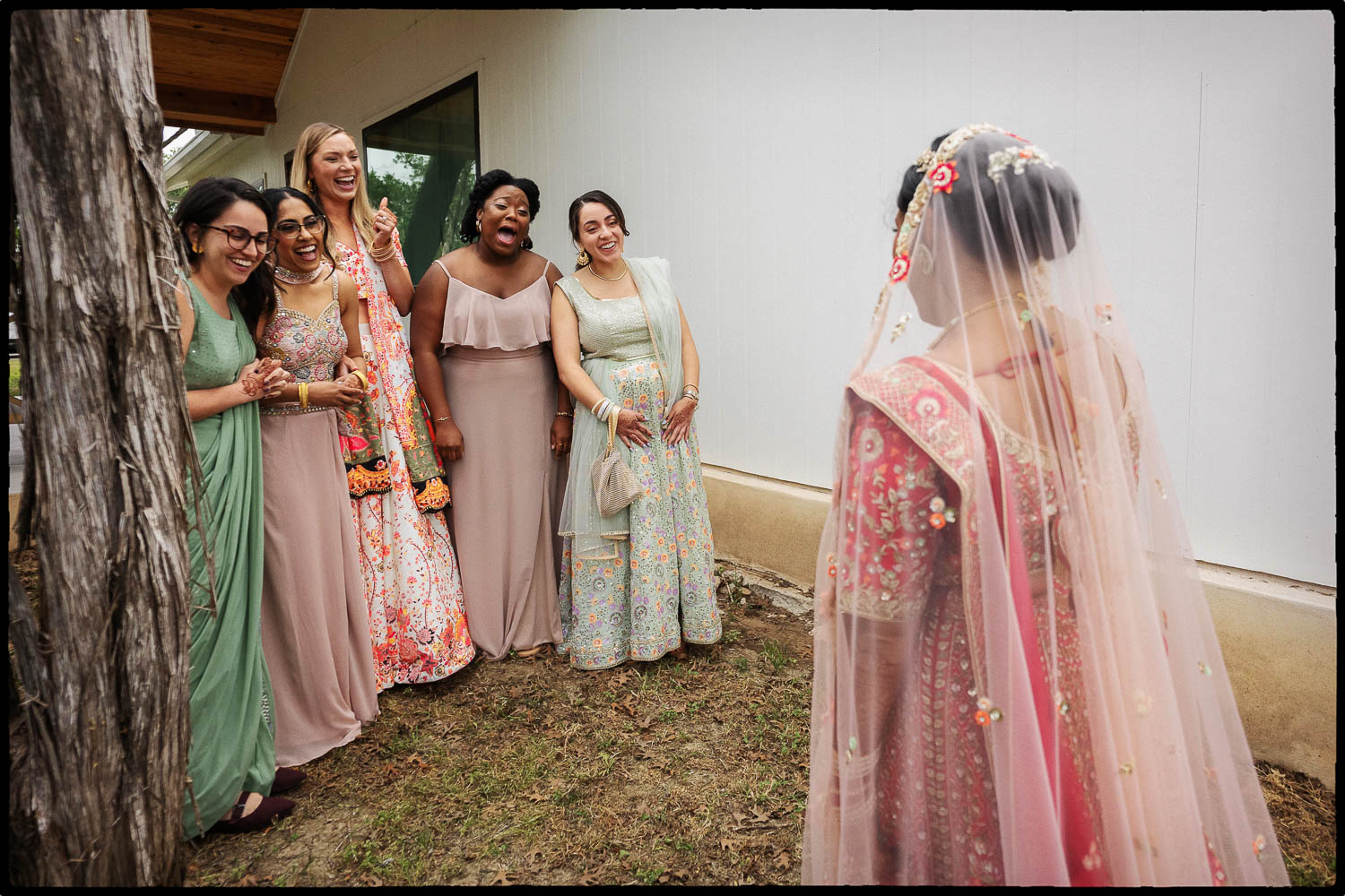 a group of women in dresses greets the bride for first look