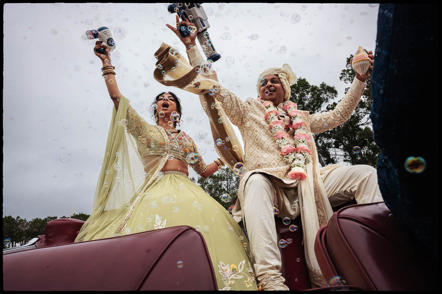 a man and woman in traditional indian attire holding bubble guns