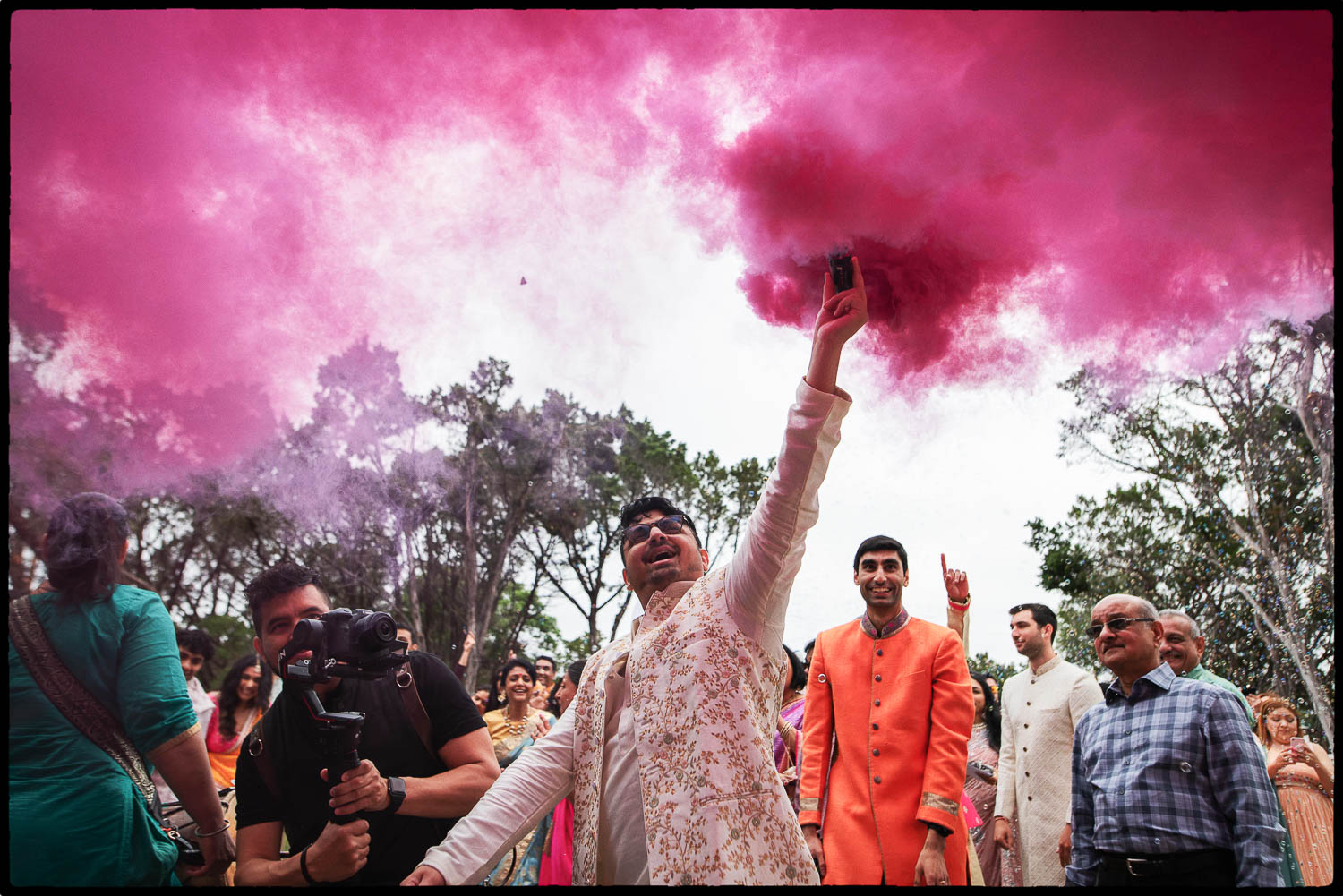 a man holding a smoke bomb up in the air with a group of people in the background