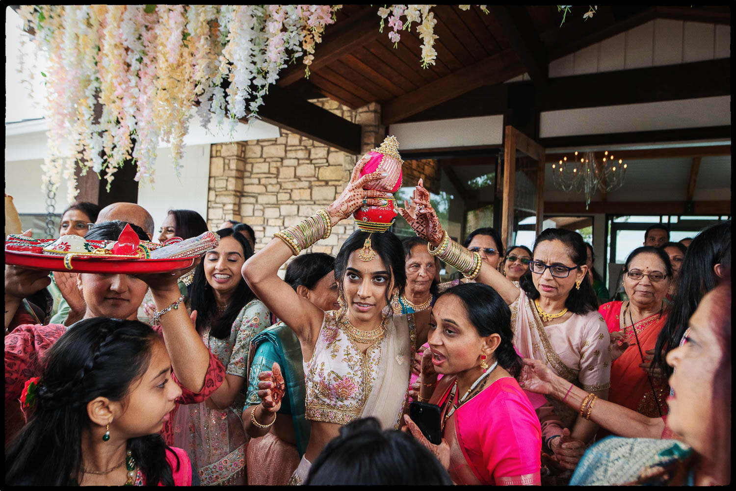 a woman holding a red object over her head during the baraat