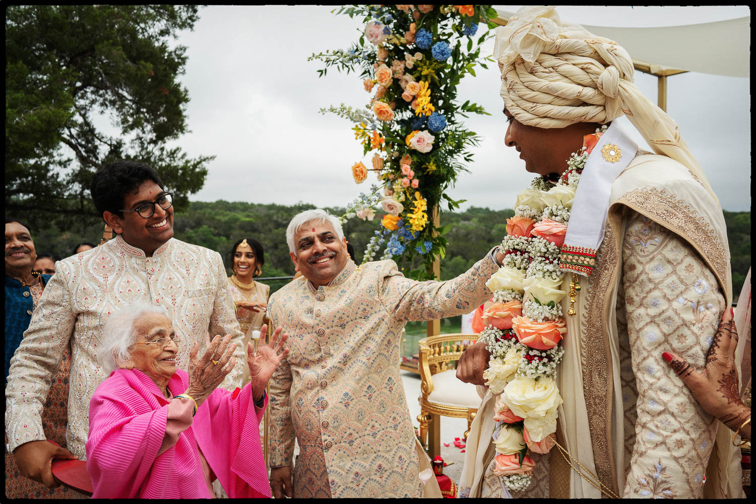 a group of people standing around a man wearing a flower garland