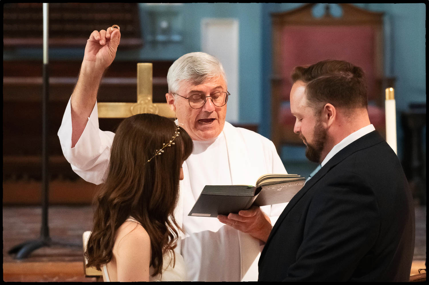 a man holding up a ring in front of a woman 15 Elopement Wedding Ceremony Travis Park Church Philip Thomas wedding photographer DSC 4631 Edit