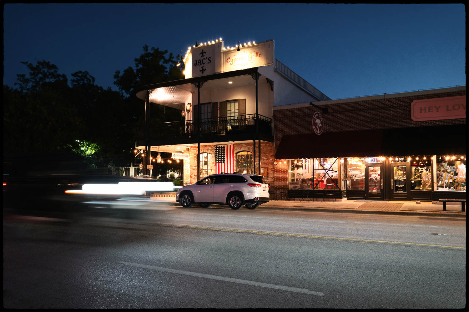 a car driving on the road past Cypress Grille in Boerne Texas