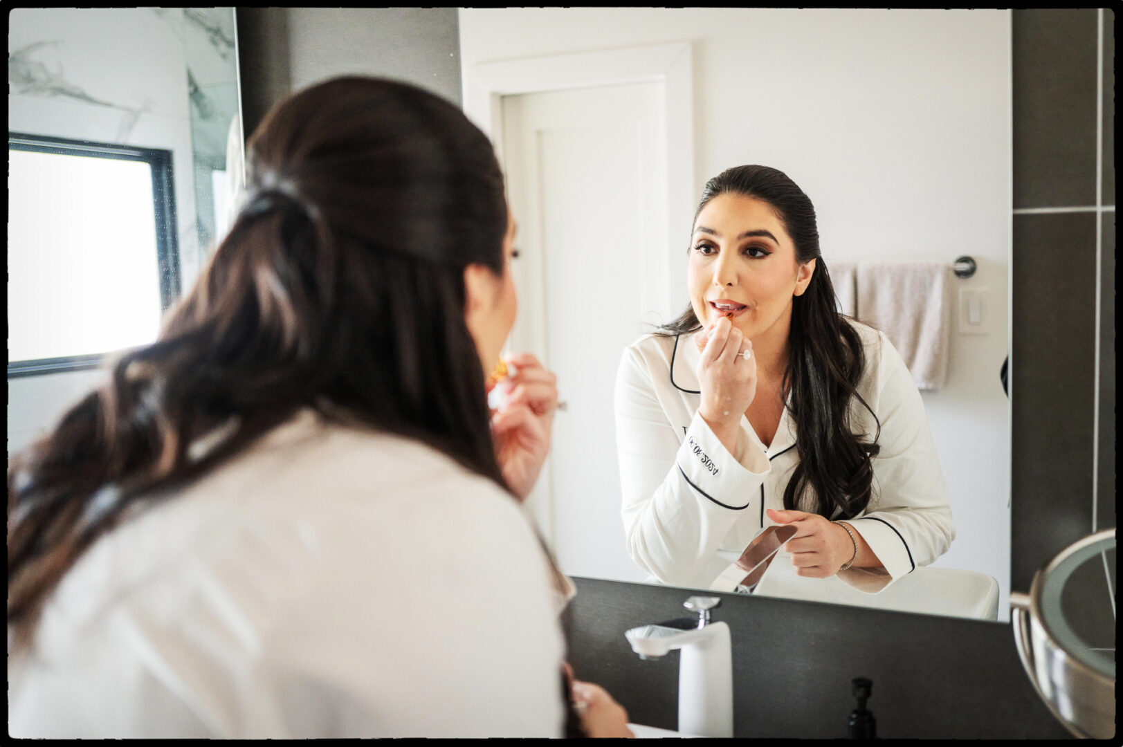 a woman applying lipstick in front of a mirror